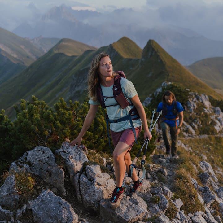 A hiker moves though the mountains with the Pursuit Series Trekking Poles and Backpack. 