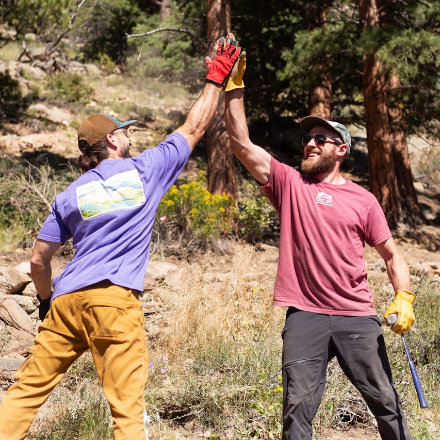 Two trail workers high five over a job well done.