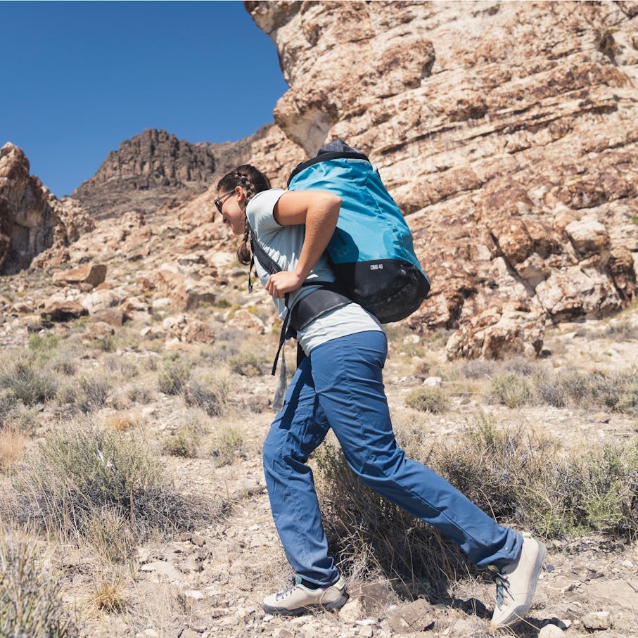 Woman hiking in the desert wearing the Technician Alpine Pants and a Black Diamond backpack