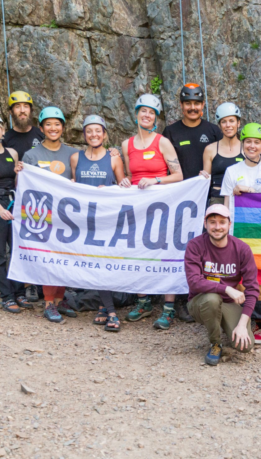 SLAQC. A group of climbers holding a flag for SLAQC and PRIDE.