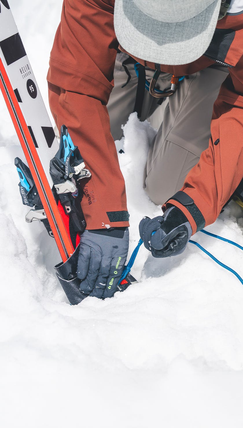 A man secures a snow anchor in snow