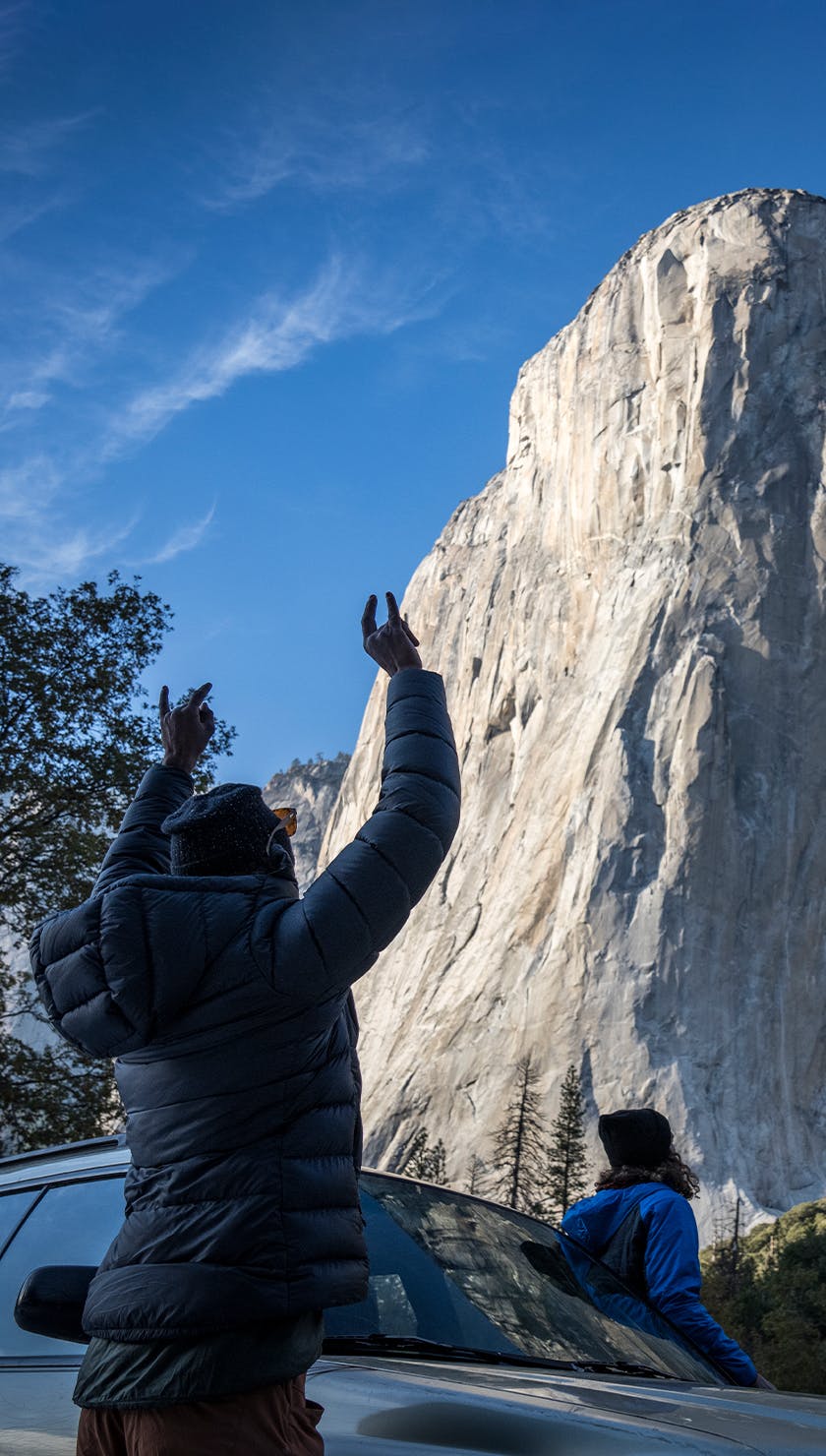 Climber raises their arms triumphantly upon seeing El Capitan 